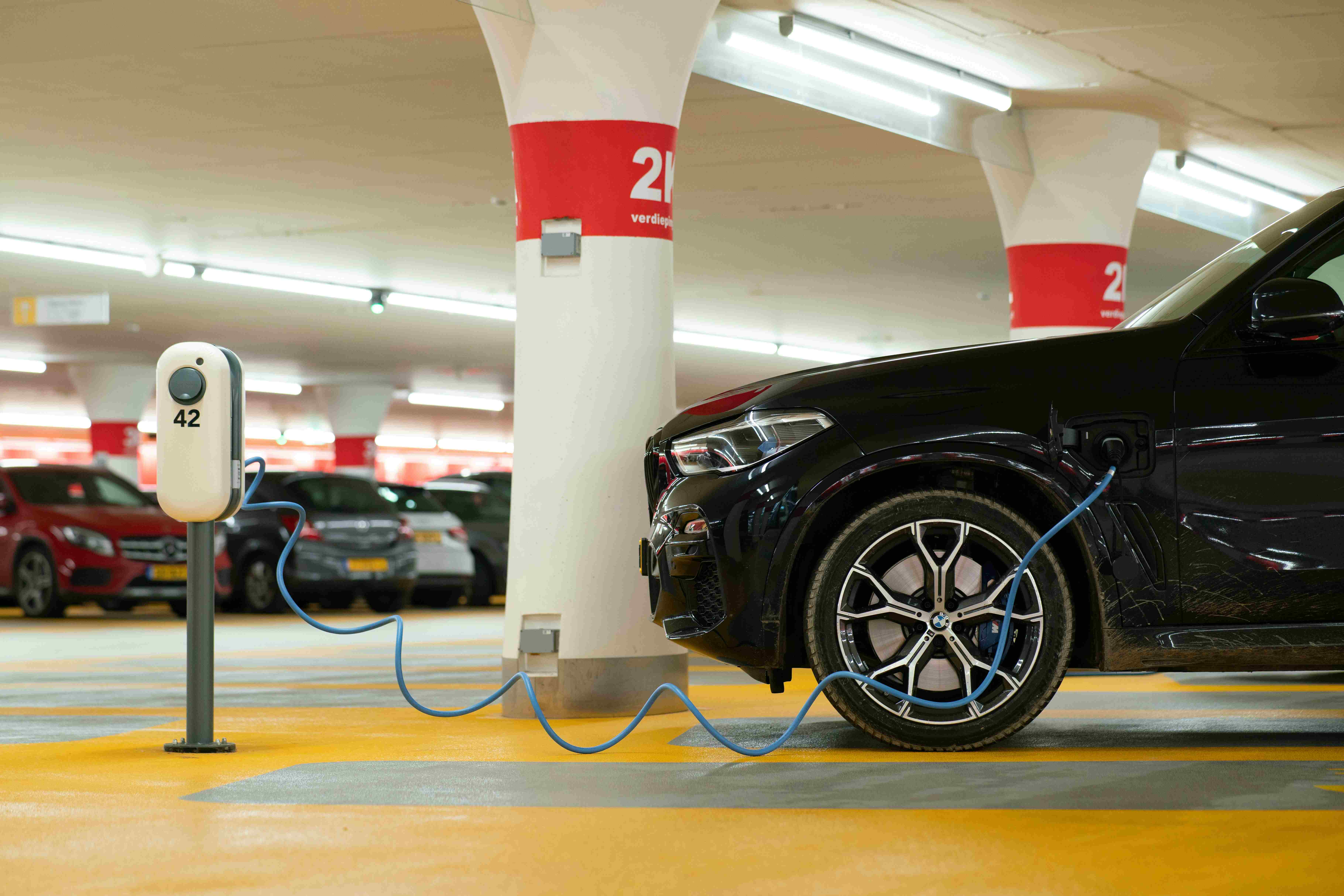 A black car charging in a parking lot